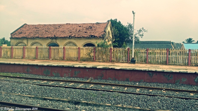A picture of an old abandoned building near a railway track